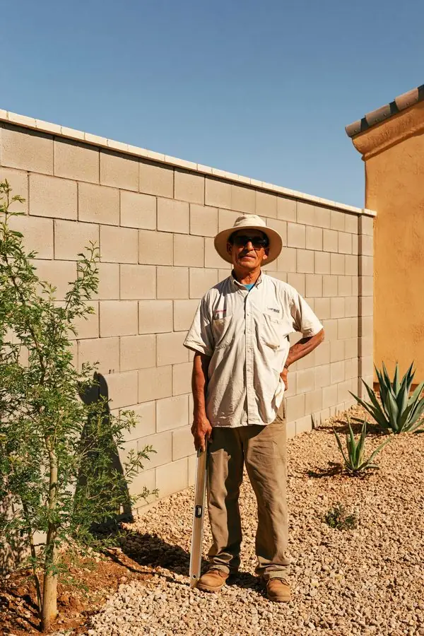 Block wall contractor in Tempe, AZ standing beside a newly finished tan block wall with a clean cap